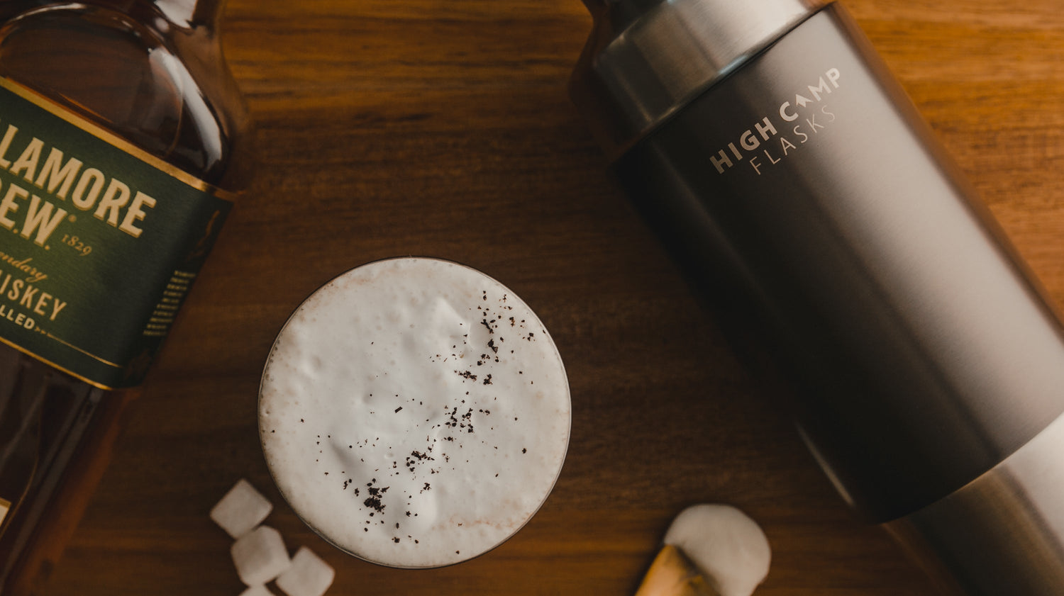 Irish Coffee in a camping tumbler next to a vacuum insulated firelight flask that fits a whole bottle of whiskey, wine and cocktails